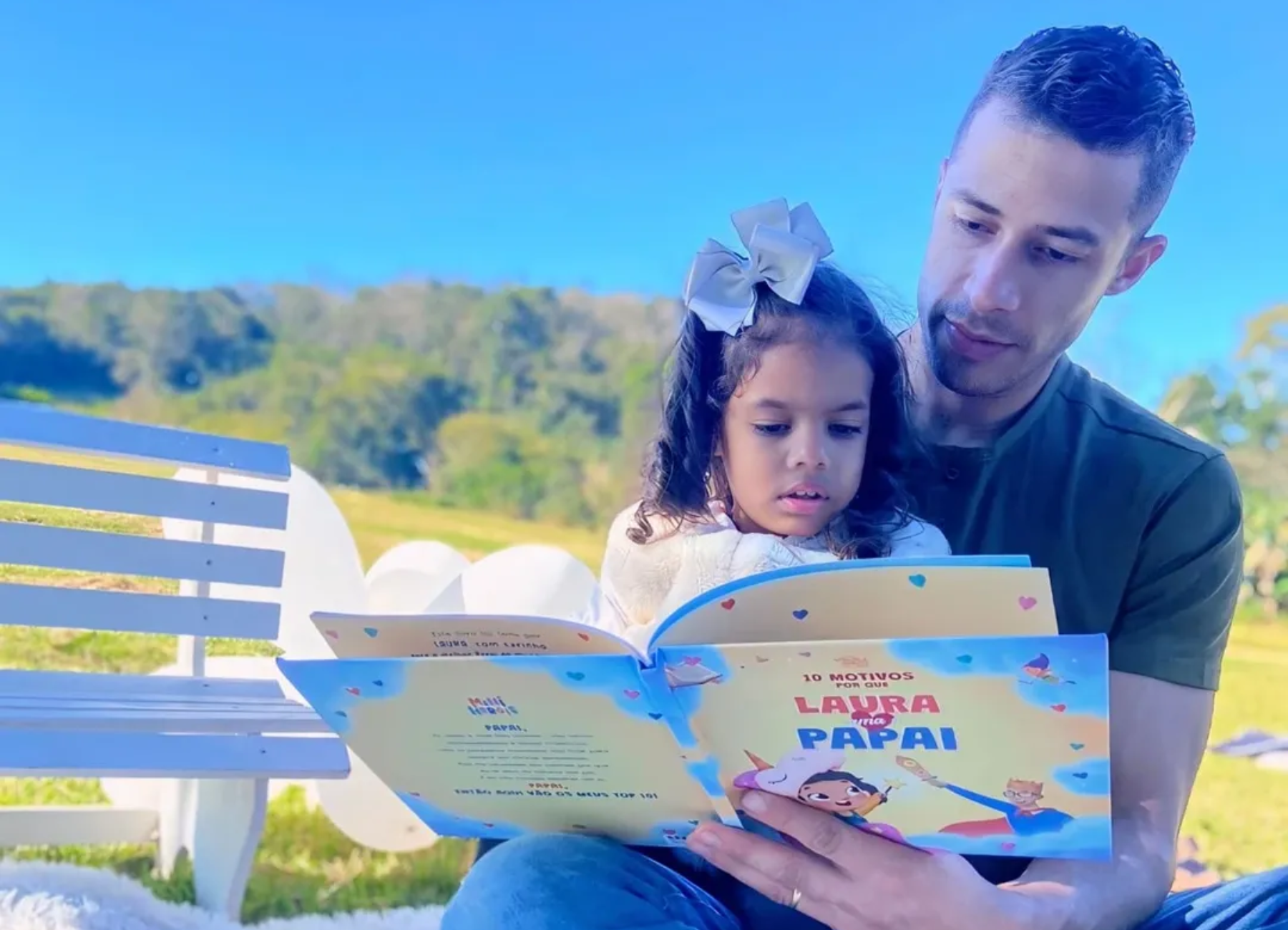 Pai e filha sentados juntos lendo o livro em que os dois são personagens